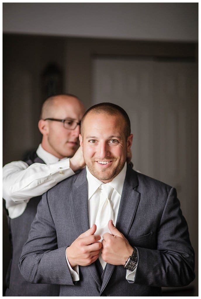 A groomsman's duty being perfectly attended to - help the groom look immaculate.