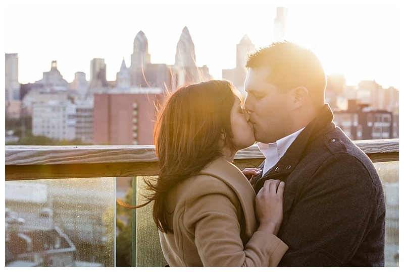 A golden sunset over the Philadelphia skyline is a perfect backdrop for a romantic kiss.