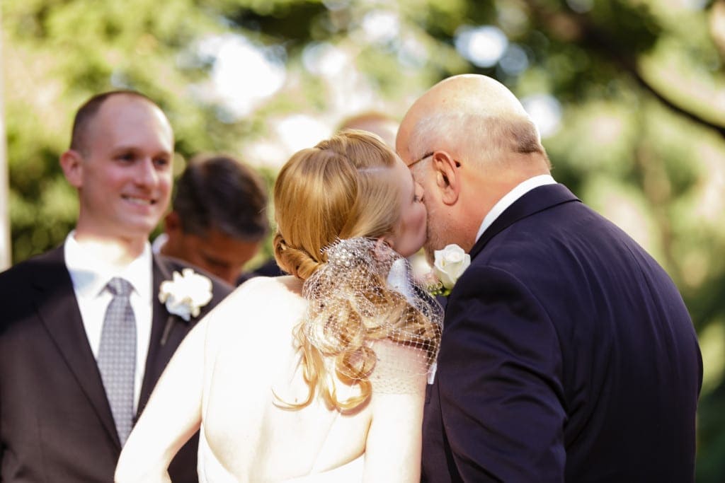 A kiss for dad as he gives his daughter away.