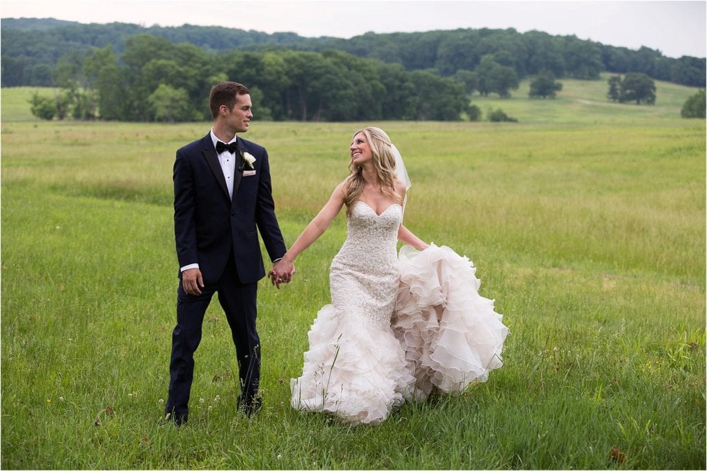 bride and groom walking through fields in the summer at Valley Forge PA