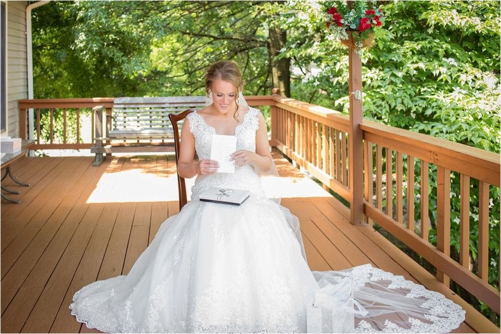 Bride opening letter from groom on wedding day, sitting on outdoor deck. Wedding in central PA