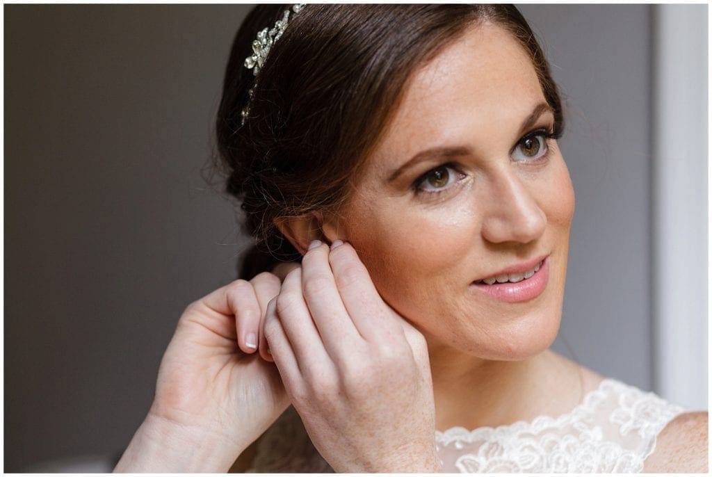 Photo of bride putting earrings on during her getting ready photos in NJ