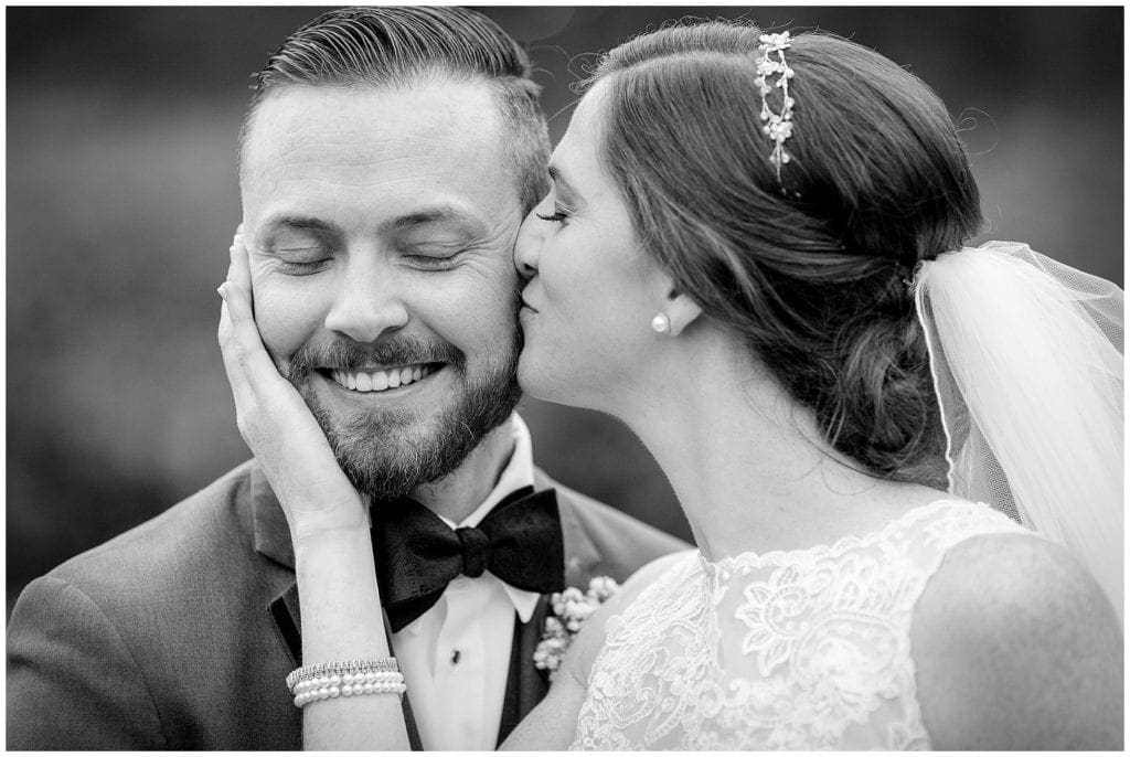 sweet moment on wedding day photo of bride kissing groom on cheek, love the grooms reaction