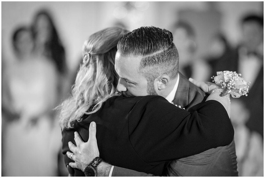 warm embrace of son and mom during parent dances at wedding reception at Farmhouse at the Grand Colonial