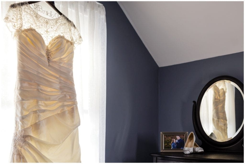 Wedding dress hanging from a window and reflected in the mirror of a vanity. Concordville wedding