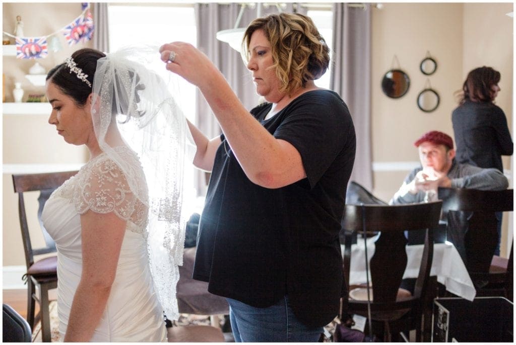 Hair stylist adjusting the bride's veil for getting ready photos 