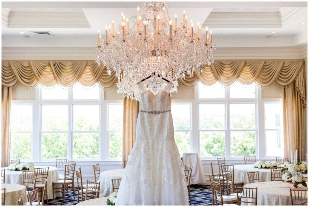 Wedding Gown hanging from custom hanger on chandelier in the ballroom at a Trump National Philadelphia wedding.