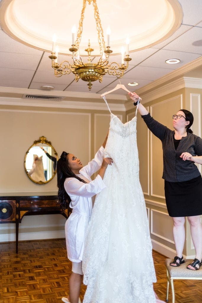 Behind the scenes of hanging the wedding dress on a chandelier.
