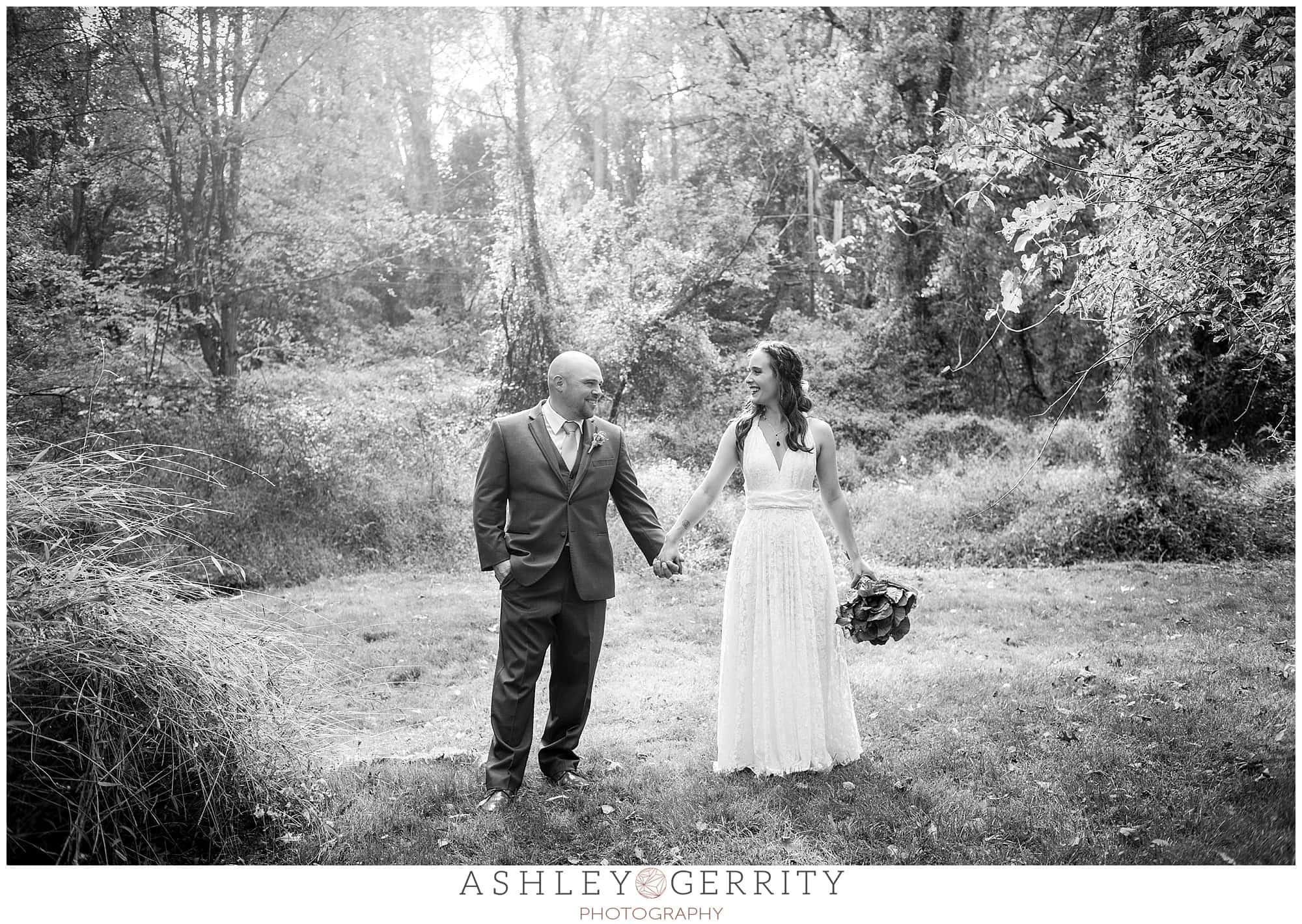 Bride & groom happily embracing in a field during their Chester Springs wedding in black & white