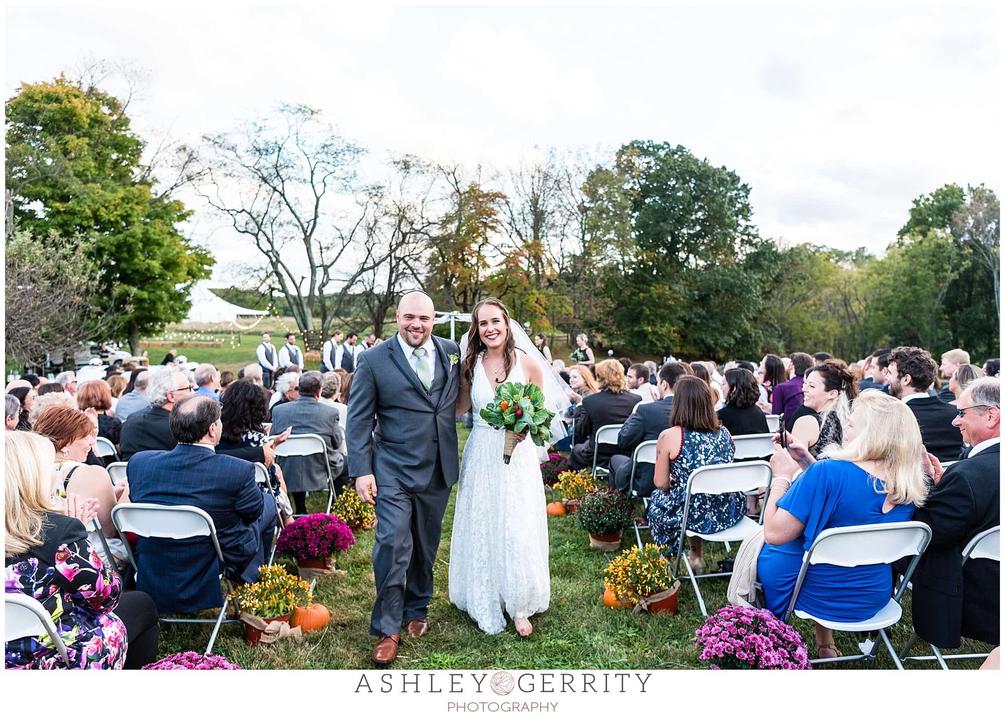 bride & groom exit their outdoor autumn Chester Springs wedding ceremony together.