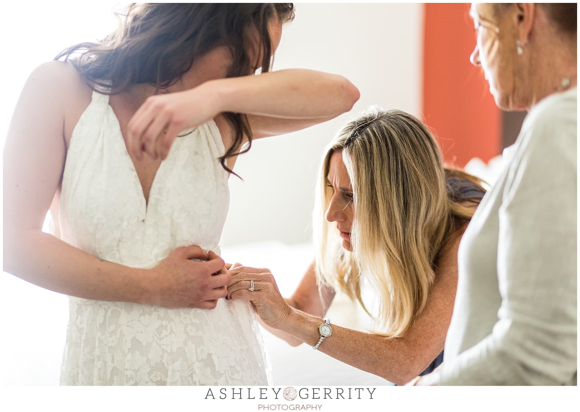 Bride gets into her wedding dress with mother & grandmother