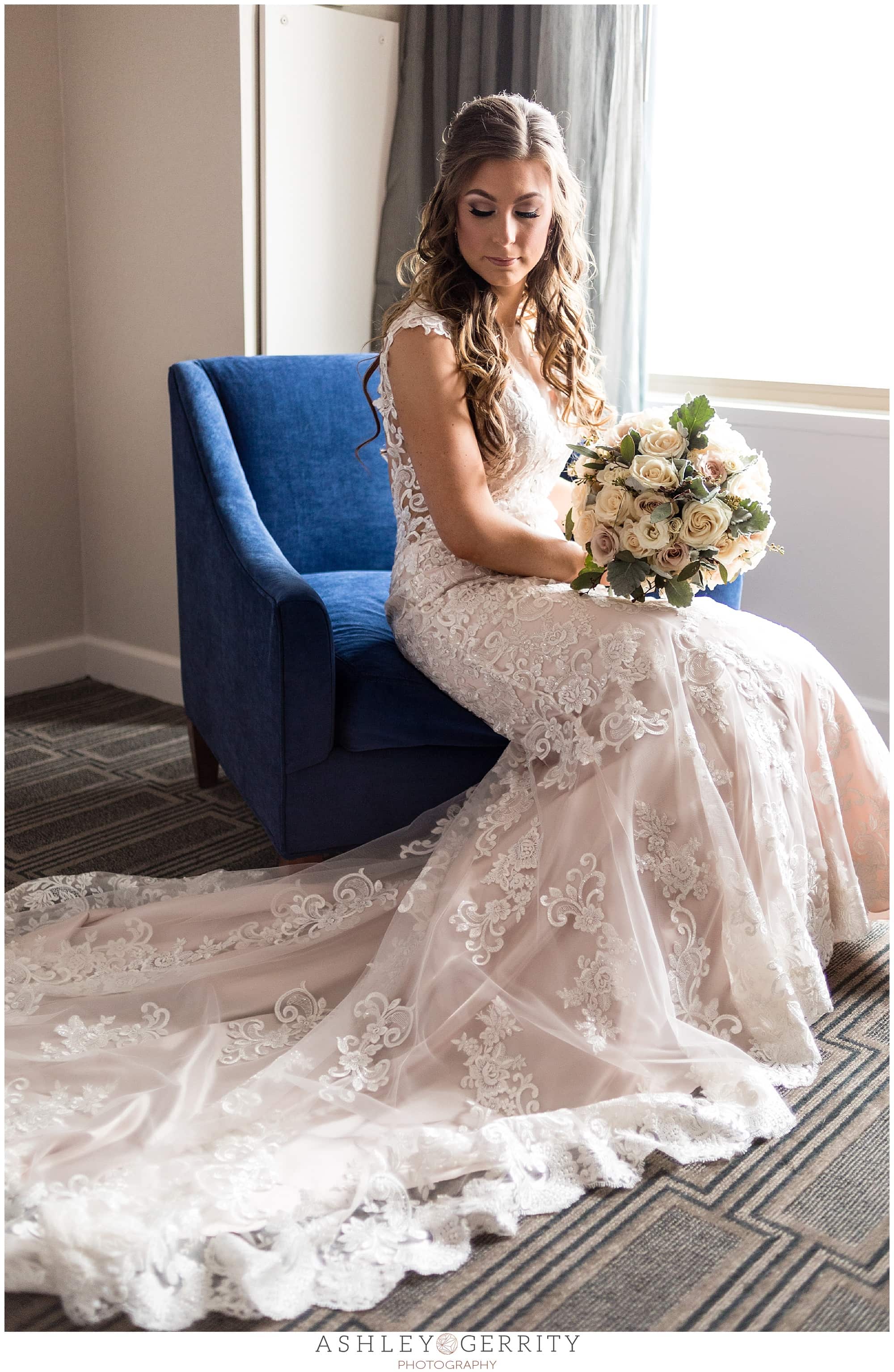 Bride with Beautiful Blooms bridal bouquet and long bridal gown train sitting portrait