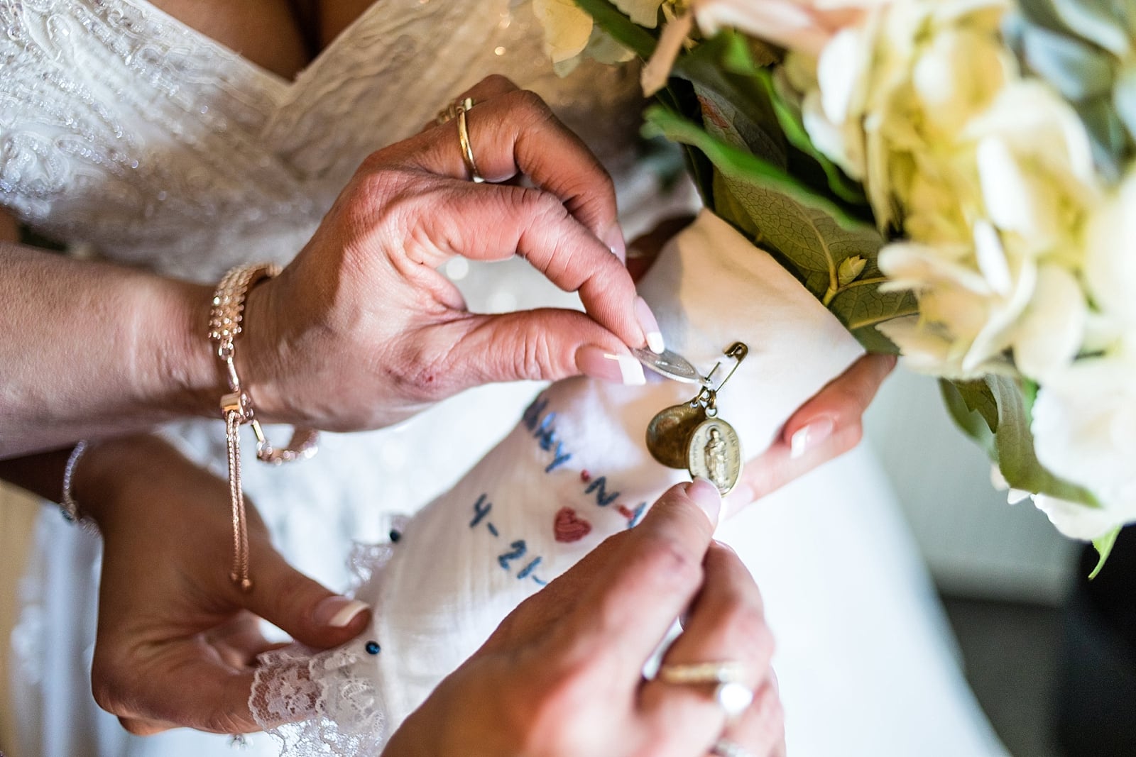 Bride & her mother attach charms to her bouquet, wrapped in a custom embroidered handkerchief.