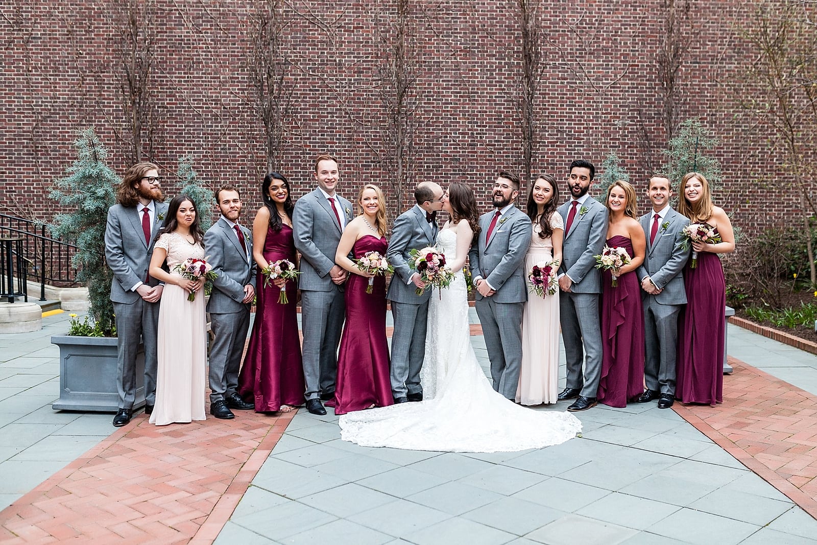Groomsmen and Bridal Party portrait with bride and groom kissing