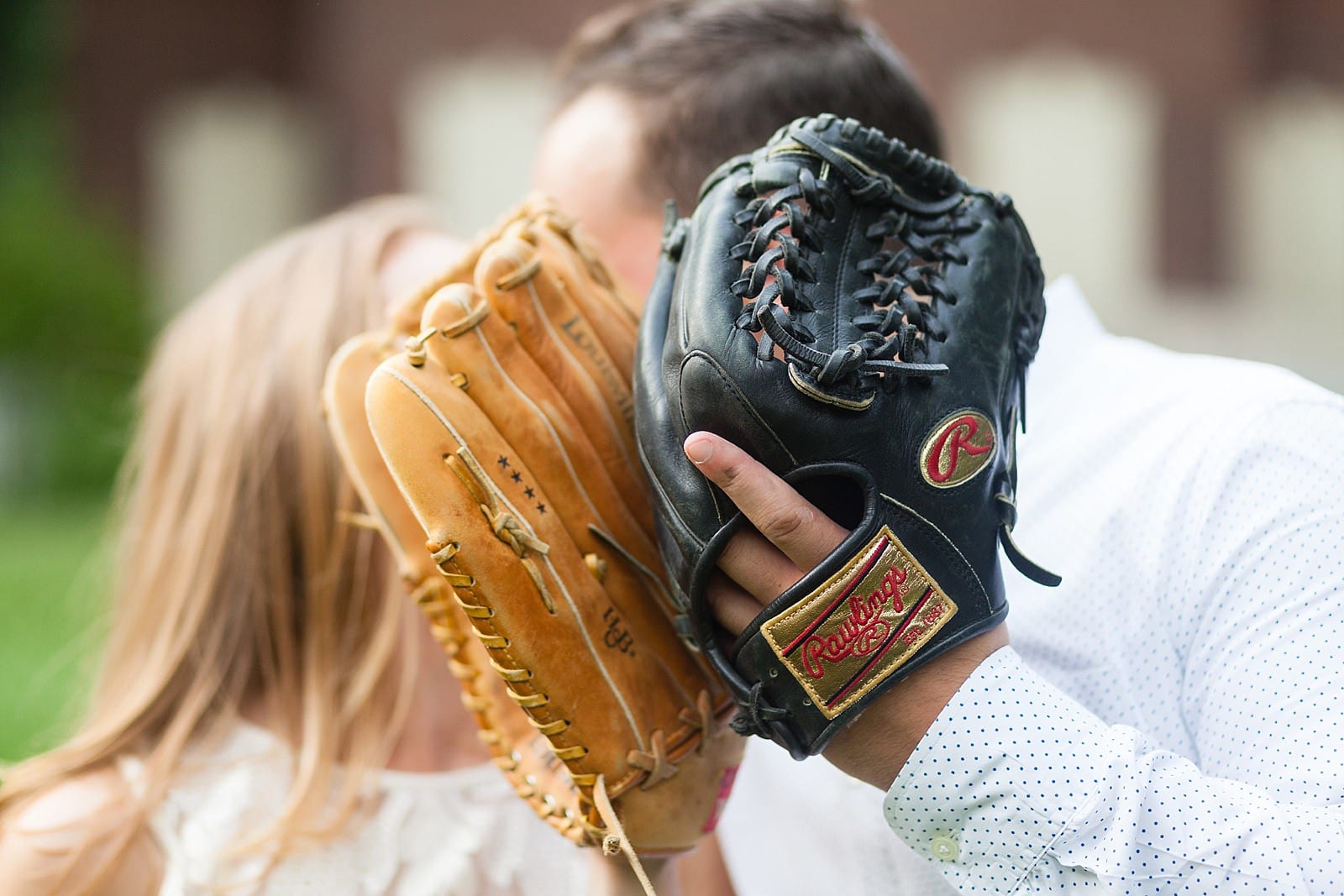 Baseball mitts, hidden kiss, intimate engagement portrait, athletic couple