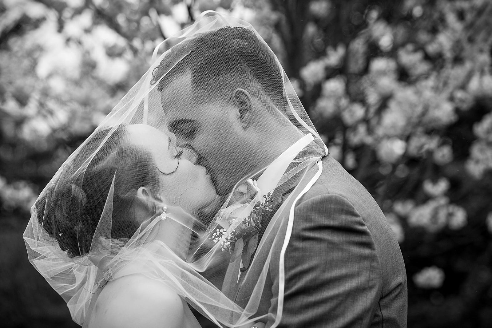 Black and white bride and groom portrait, bride and groom kissing under veil 