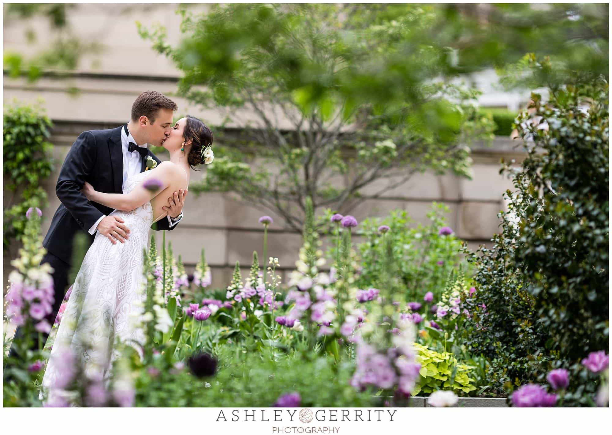 Bride and groom portrait, groom dipping and kissing bride, shot through flowers, Free Library wedding