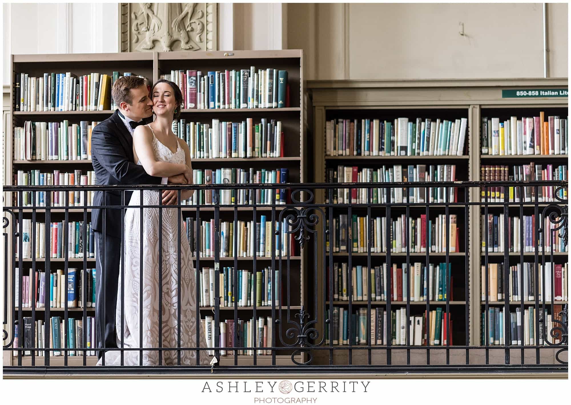 Groom hugging bride from behind and laughing, bookshelf portraits, Free Library wedding