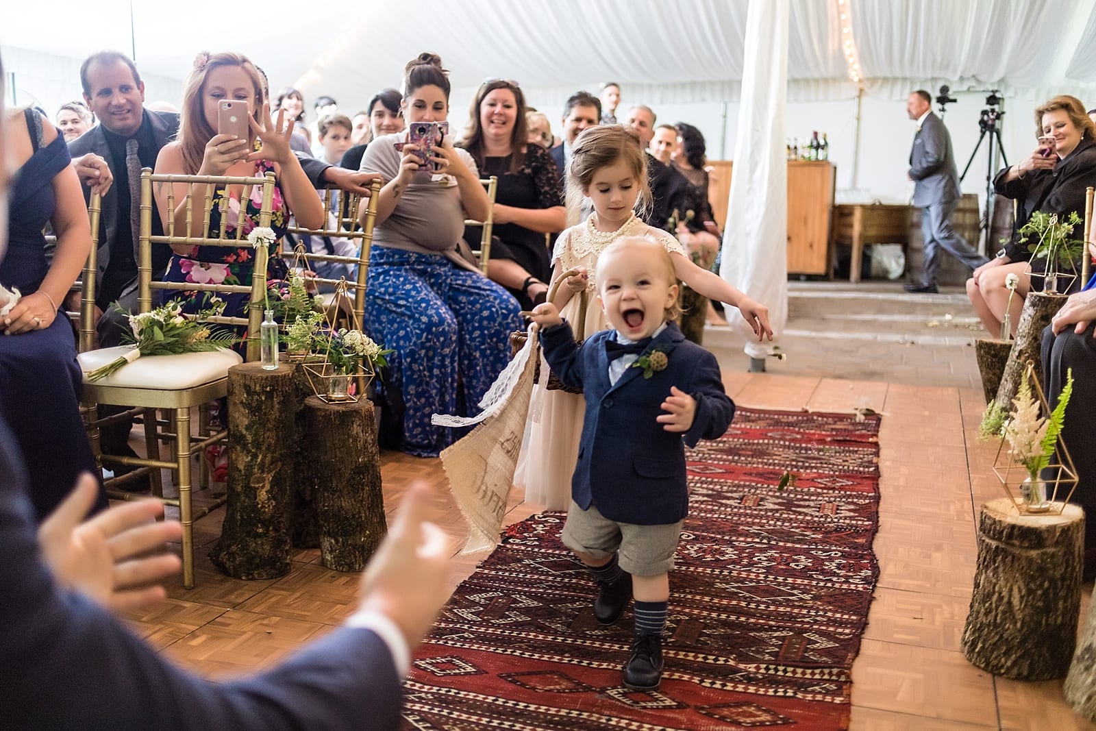 Groom reaches out for his children, the ring bearer and flower girl, as they run down the aisle