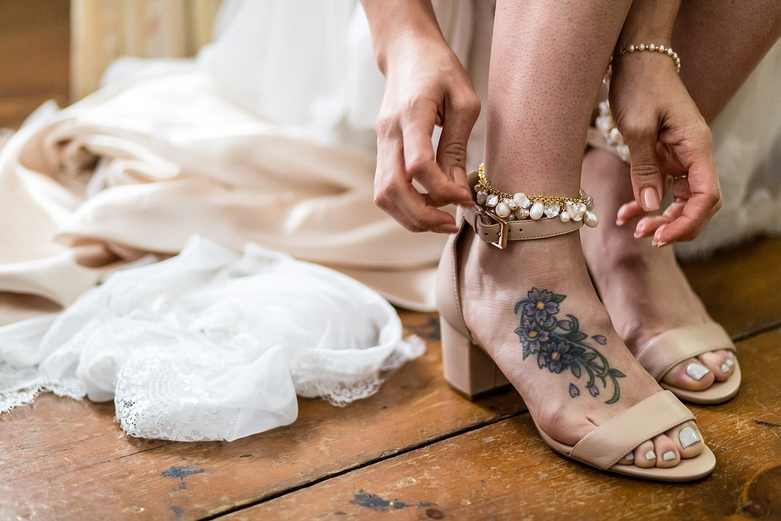 Tattooed bride puts pearl anklet on as she gets ready for her wedding