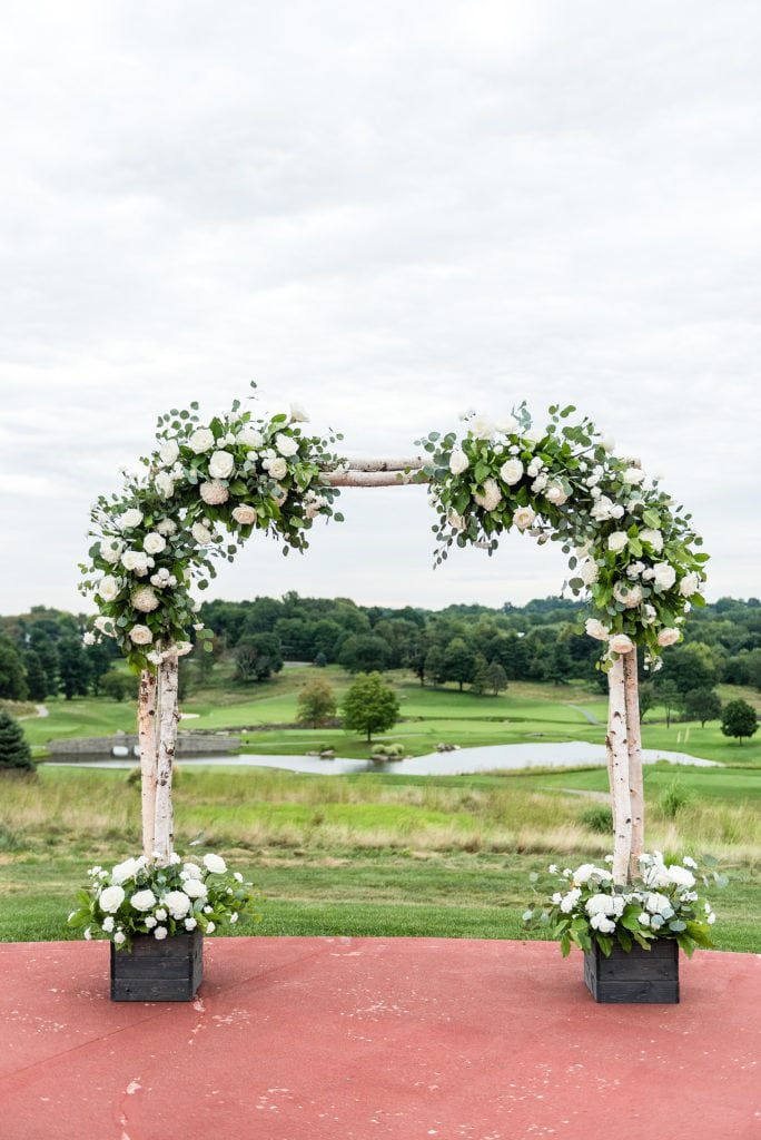 Wedding ceremony arch made of raw wood and rose arrangements