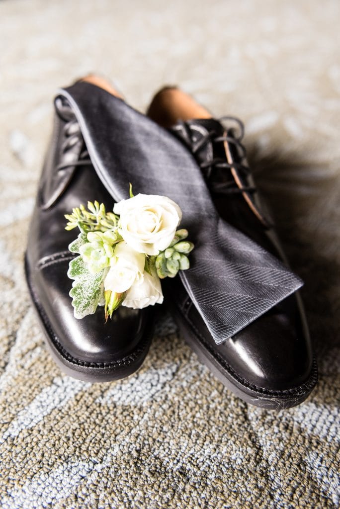 Boutonniere and bowtie on a groom's dress shoes