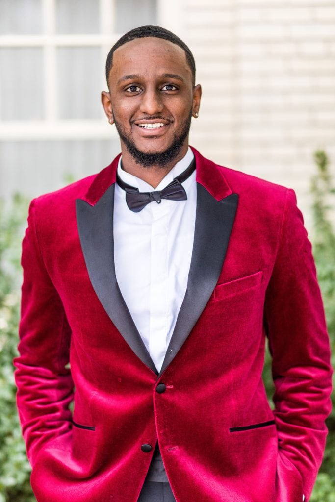 Portrait of a groom in a red crusted velvet jacket with a black lapel