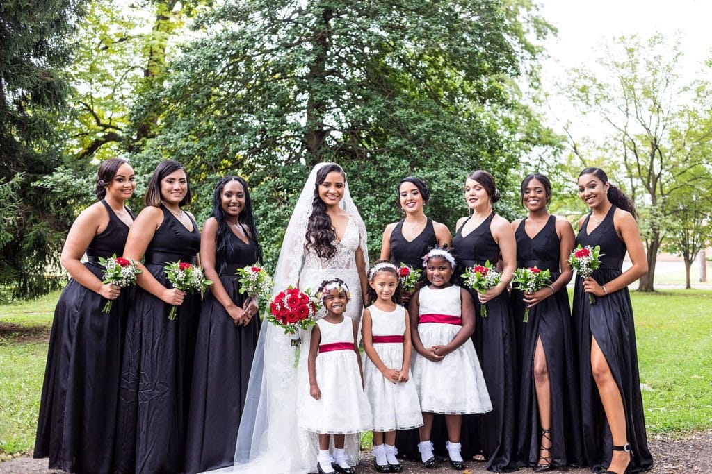 Bride wearing her Galina Signature wedding dress, with her bridesmaids dress in black and three flower girls in white pose together before her Collingswood Ballroom wedding