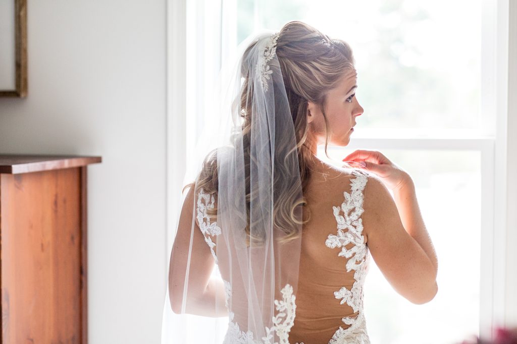 Bride looks over her should to show off the illusion lace back of her Watters wedding dress