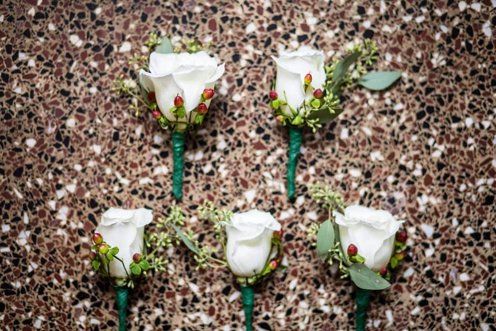 White rose and red berry boutonierre on a tiled background