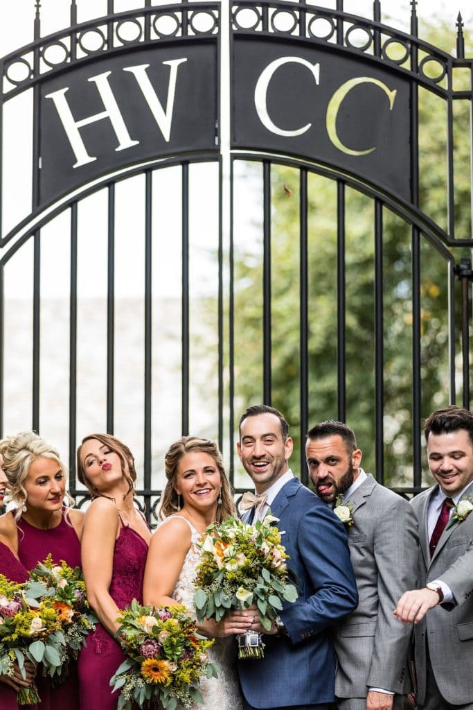 Bride & groom and their wedding party posing in front of the house and the gate at Huntingdon Valley Country Club