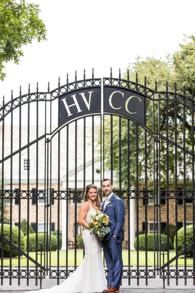 Bride & groom smile for a wedding portrait in front of the gate at Huntingdon Valley Country Club