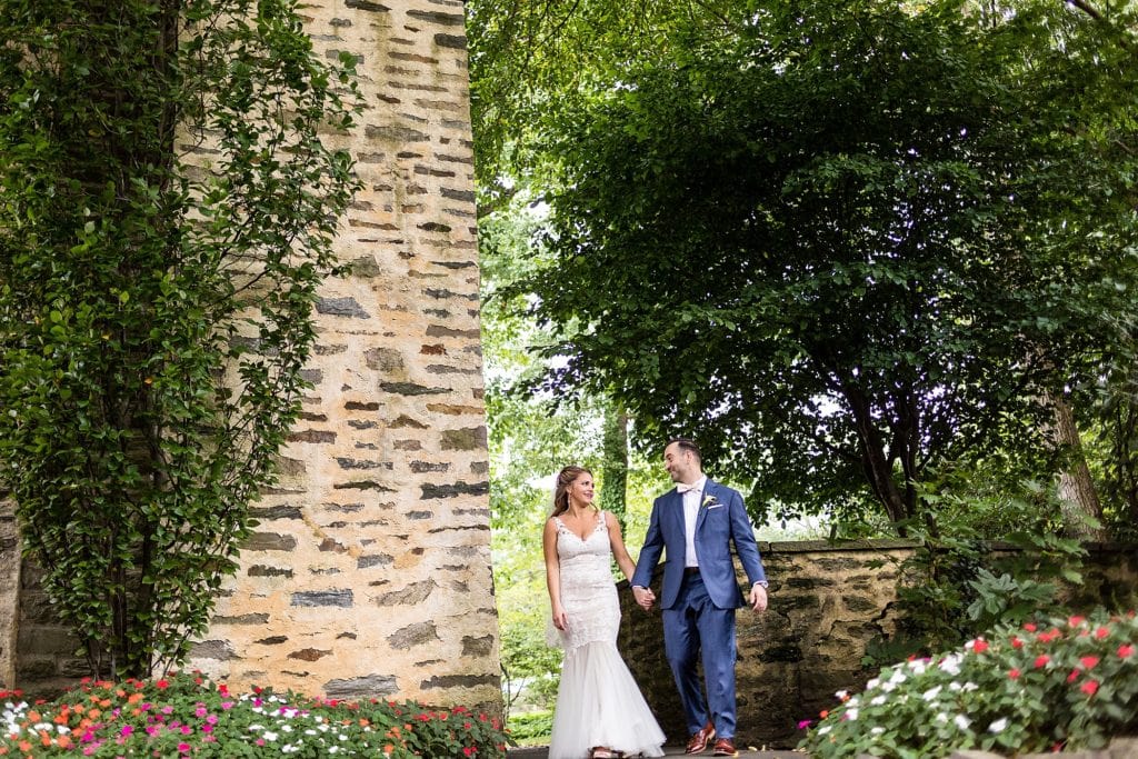 Bride & groom walk while holding hands during their Huntingdon Valley Country Club wedding