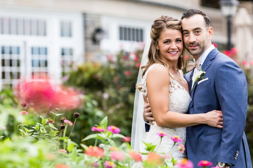 Bride & groom smile for a wedding portrait in the flower gardens at Huntingdon Valley Country Club