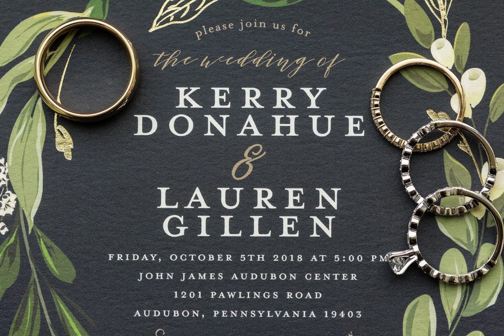 Wedding rings on a black wedding invitation inspiration with green vines and white print