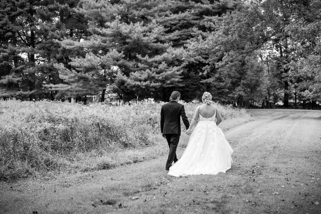 Bride & groom walking away from the camera while holding hands after their John James Audubon Center wedding. Photographed in black & white.