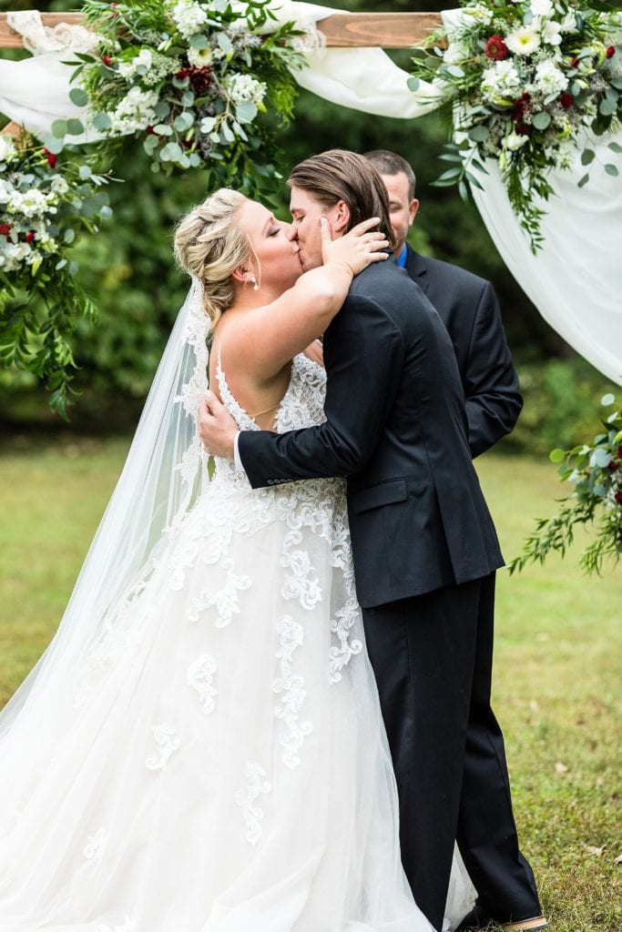 first kiss under a floral arch during an Audubon Center wedding