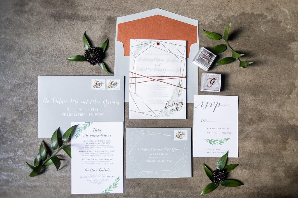 Copper & Grey wedding invitation for a Kimmel Center Wedding by Hello Bird styled against concrete with loose greenery