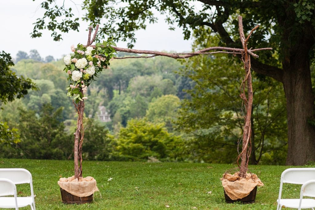 Hand-built wedding arch built from tree branches with rose arrangements