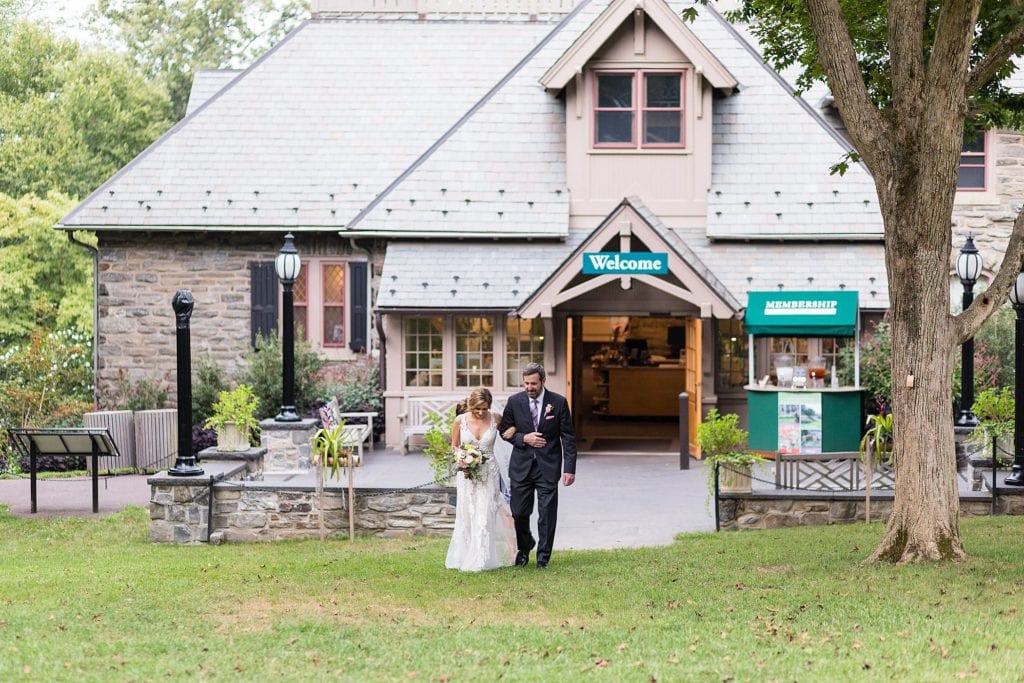 Bride walking down the aisle with her father from the Morris Arboretum welcome center