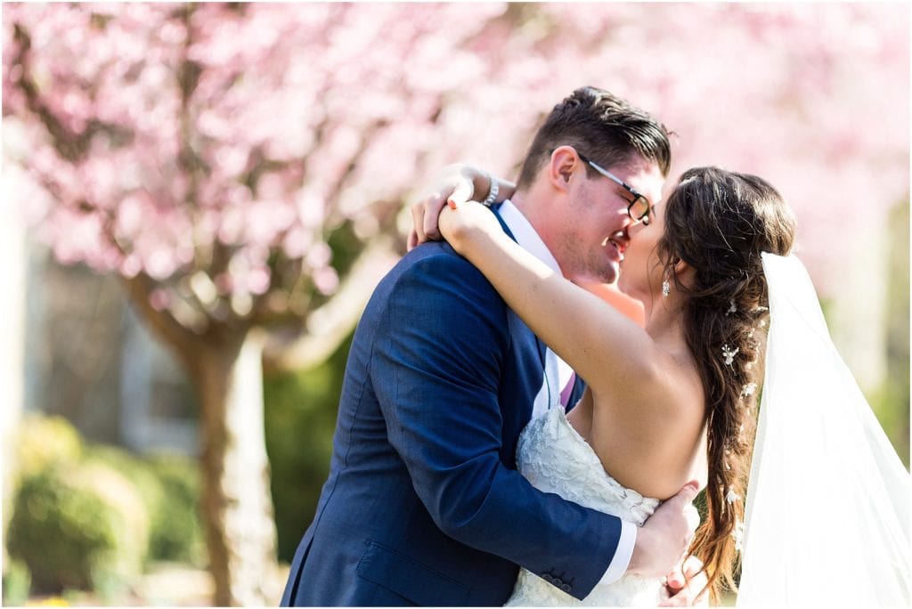 Bride in Pronovias dress sharing a kiss with her new husband surrounded by spring blossoms | Ashley Gerrity Photography www.ashleygerrityphotography.com