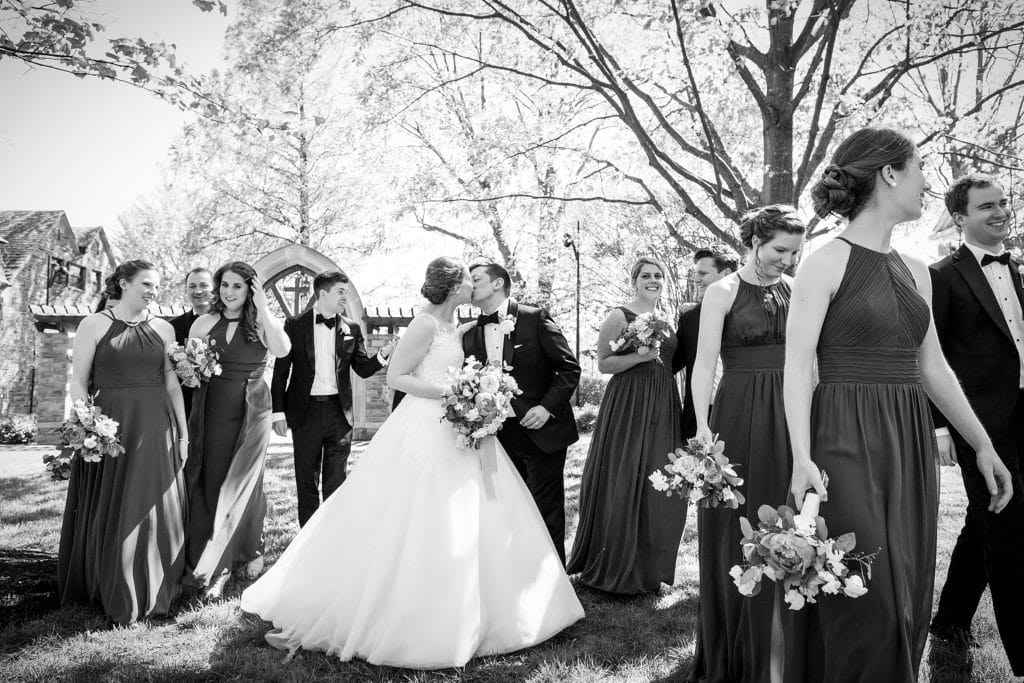 Bride and groom share a kiss surrounded by their wedding party on villanova campus | www.ashleygerrityphotography.com