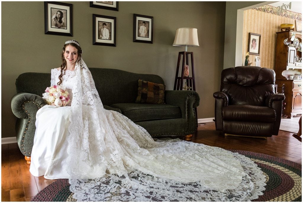Portrait of bride in her living room with train and chantilly lace veil arranged