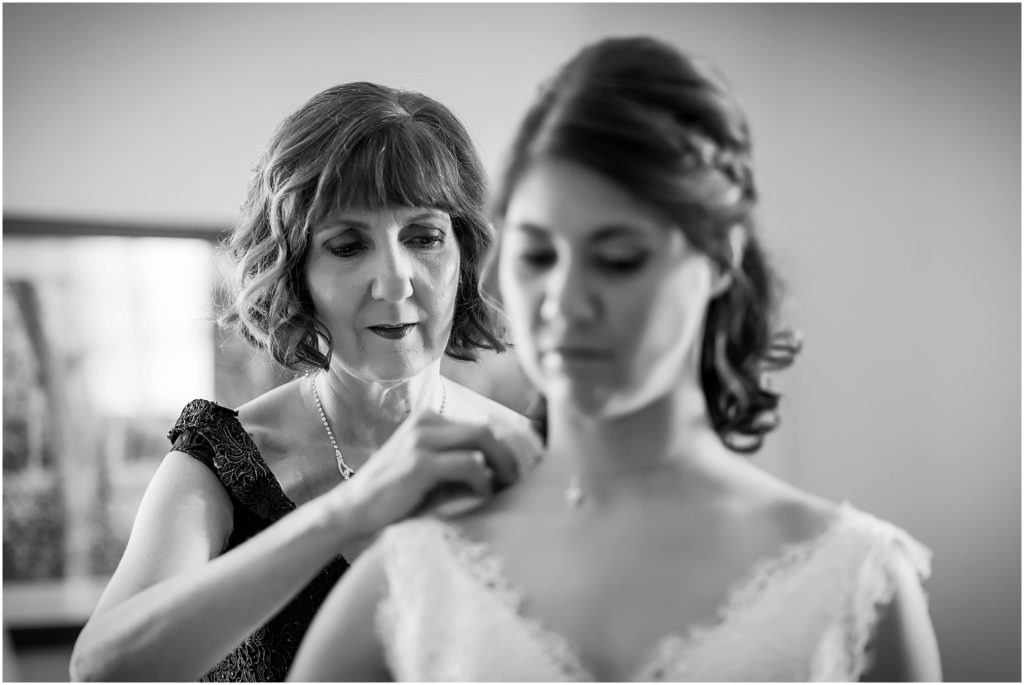 Black and white photos of Mother of the bride helping put bride's necklace on