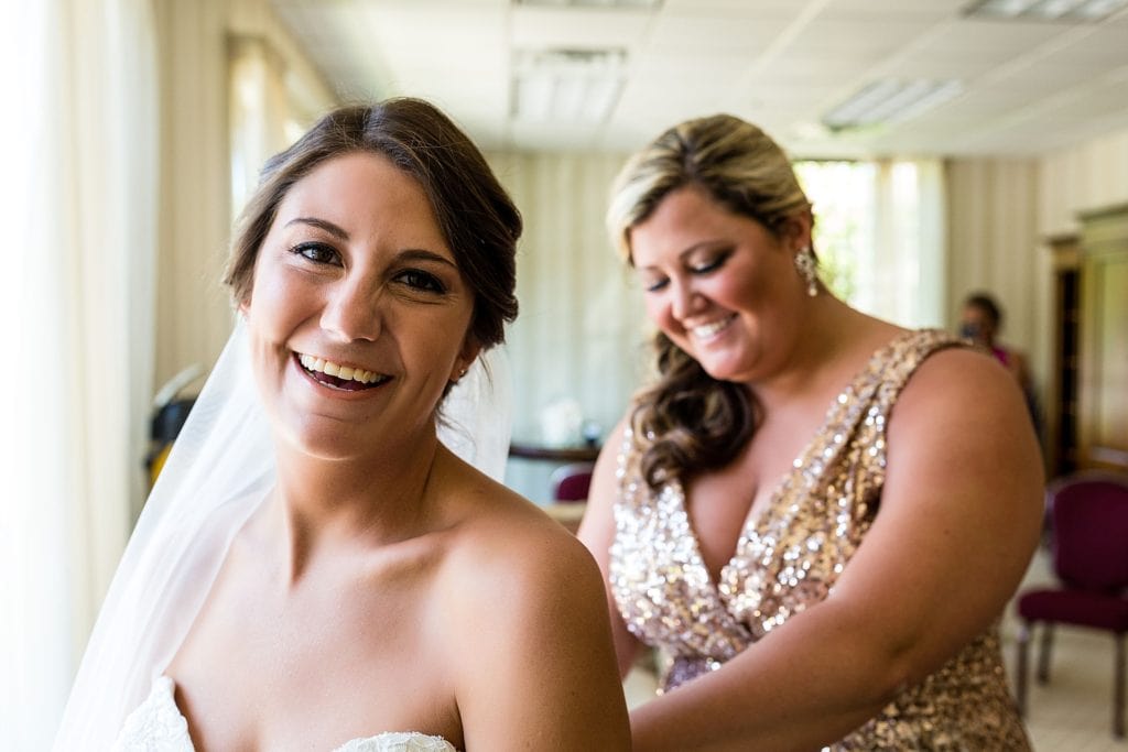 Happy bride being helped with her dress at Green Valley Country Club | Ashley Gerrity Photography www.ashleygerrityphotography.com