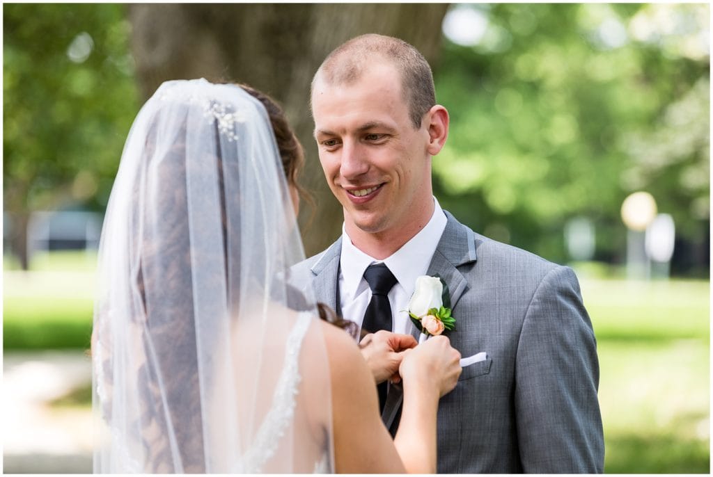 groom gazing at bride while she adjusts his boutonniere