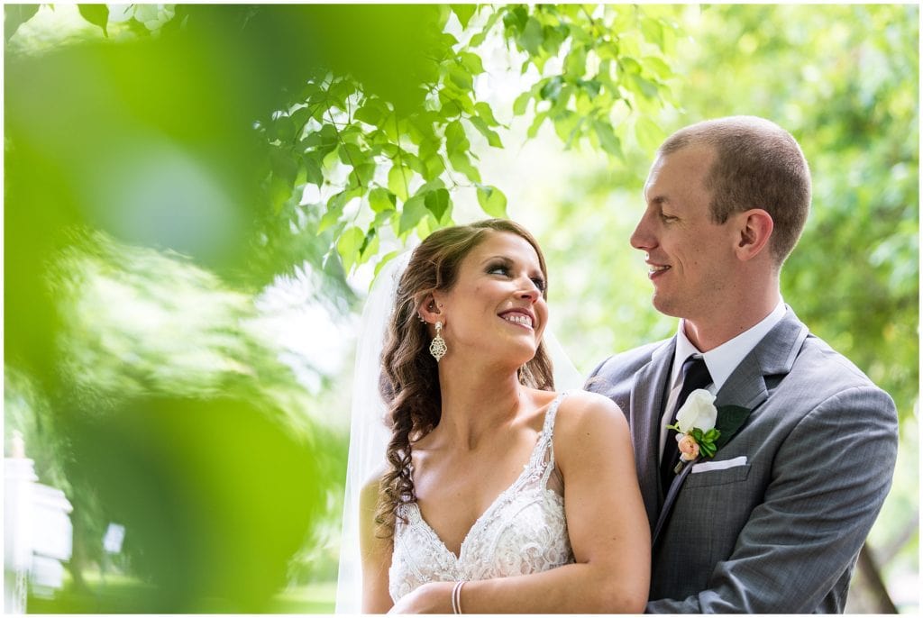 bride and groom smiling at each other through the leaves portrait