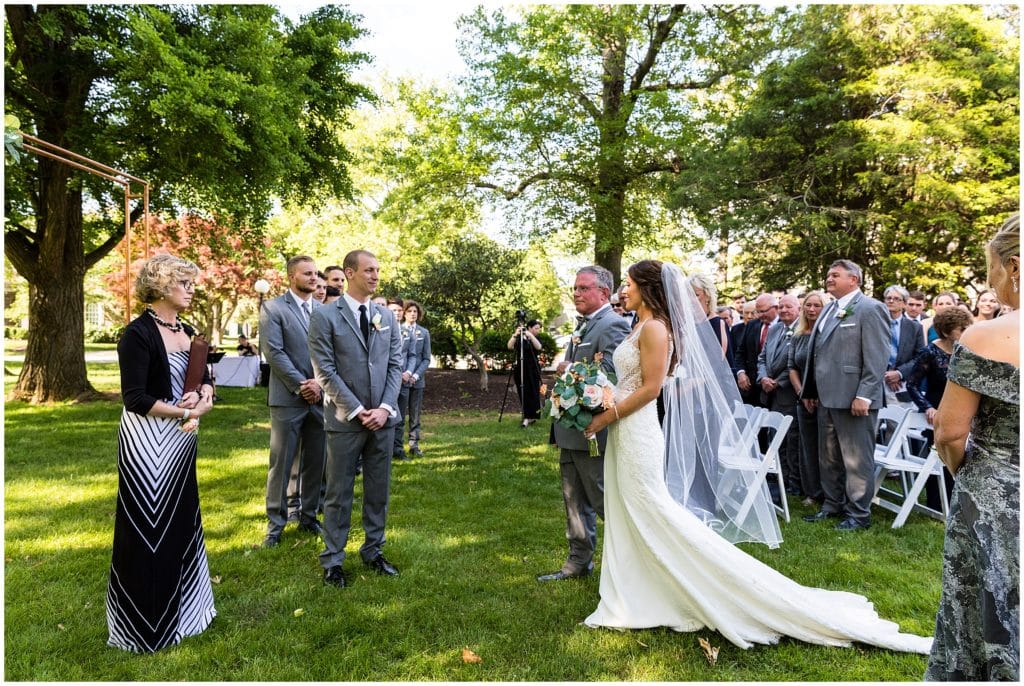 father gives bride away at outdoor wedding ceremony