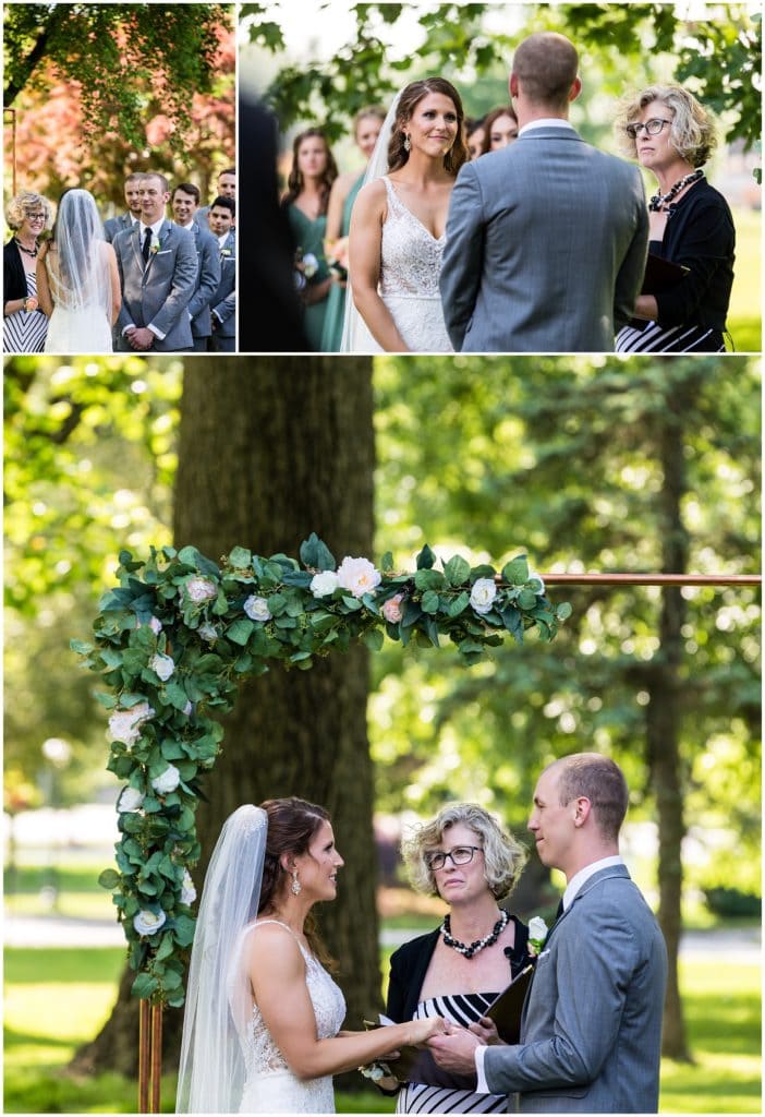 bride and groom smiling at each other during wedding ceremony with floral archway