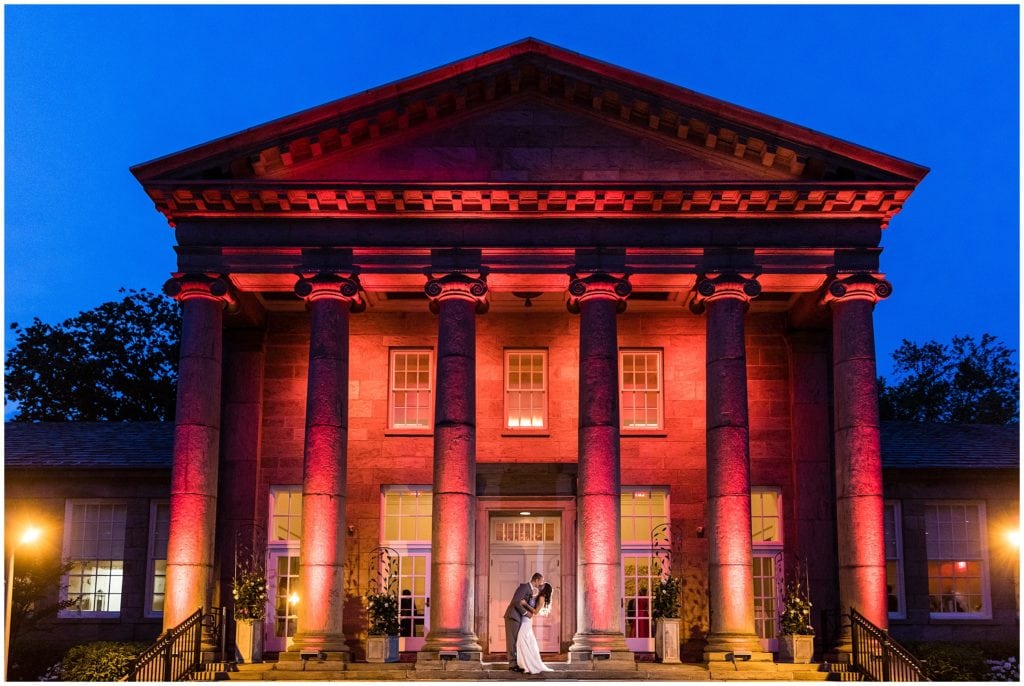 bride and groom kissing night portrait with pink lighting outside Ballroom at Ellis Preserve